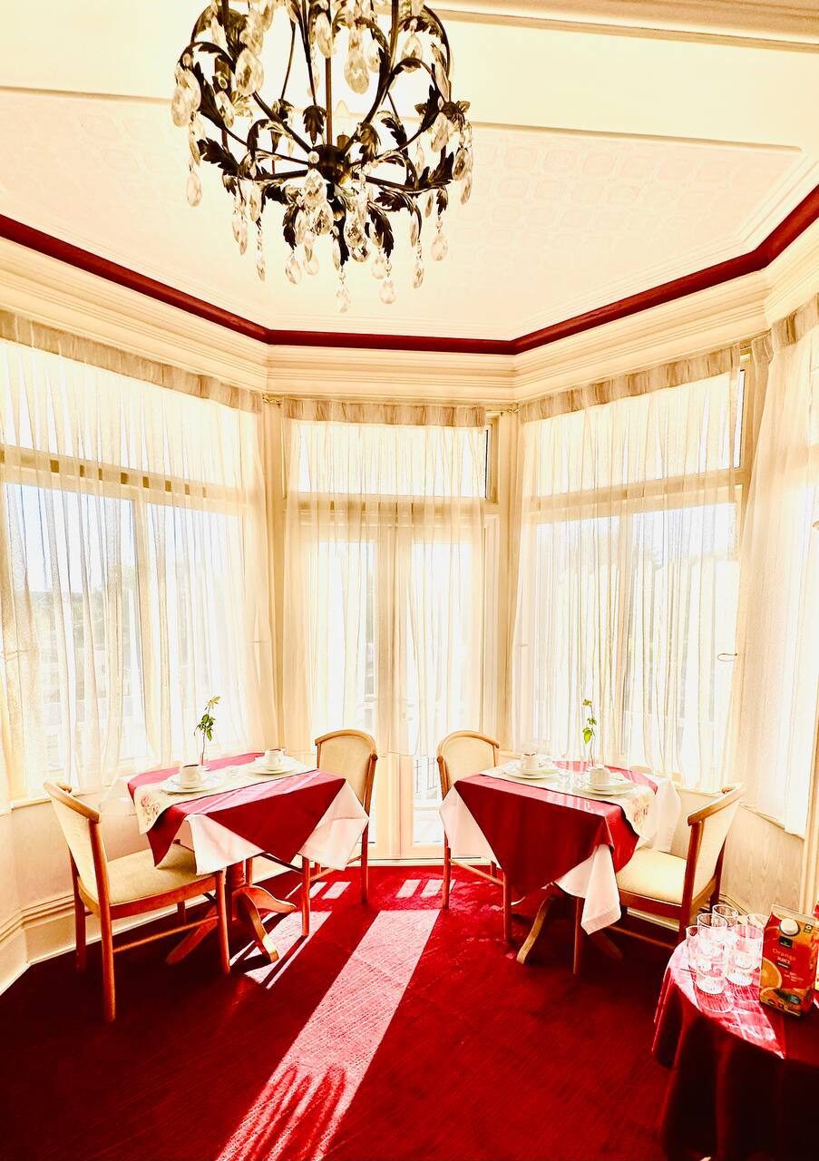 Sunlit breakfast room — tables for two set in the bay window